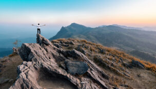 businessman success hiking on the peak of rocks mountain at sunset, winner leader concept
