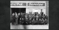 O'Meara Moters 1941 group photo: a group of men posing for a picture in front of a sign that reads "Ford Service." Black and white.