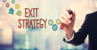 Businessman drawing Exit Strategy concept on blurred abstract background.